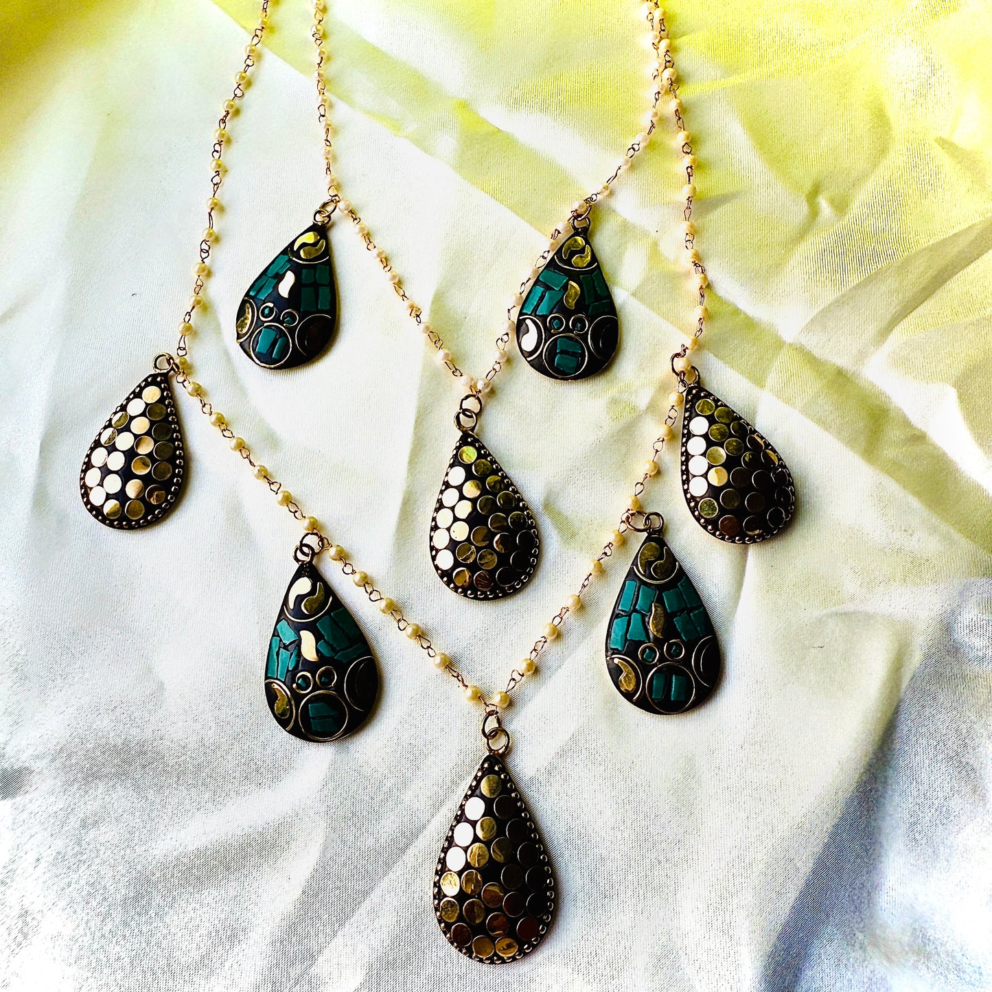 Necklace with teardrop-shaped pendants on a light fabric background