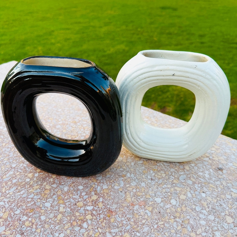 Black and white ceramic vases on a stone surface with green grass in the background