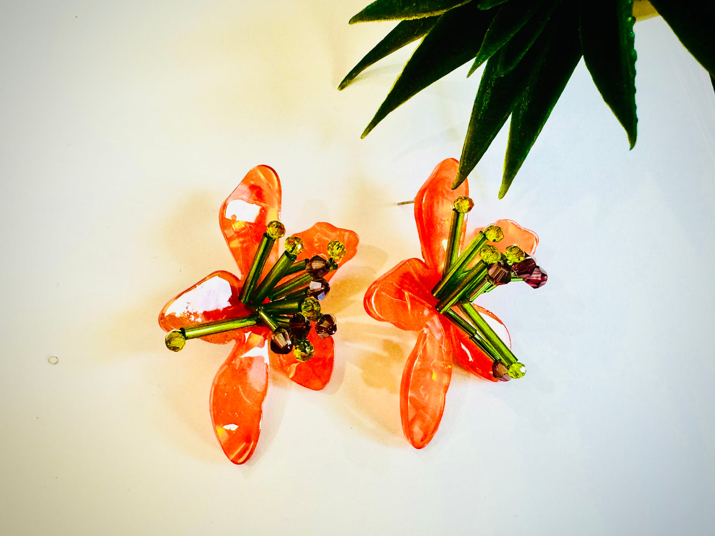 Pair of orange floral earrings on a light background