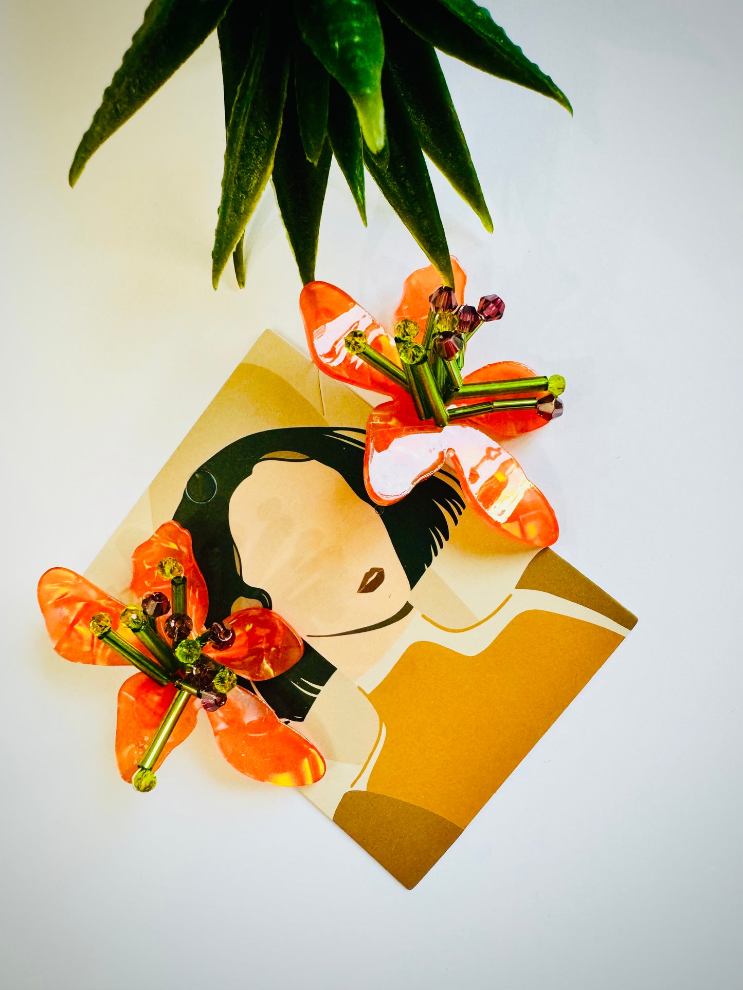 Card with a stylized illustration of a person with flowers in their hair, held by a plant.