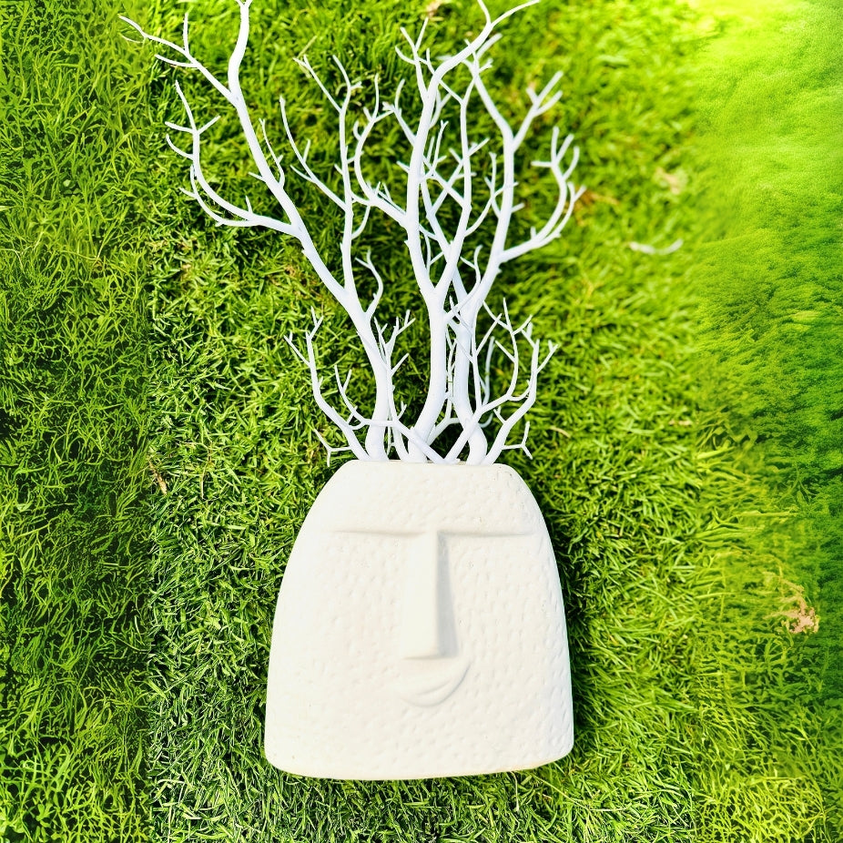 White decorative vase with branch-like structure on a green grass background