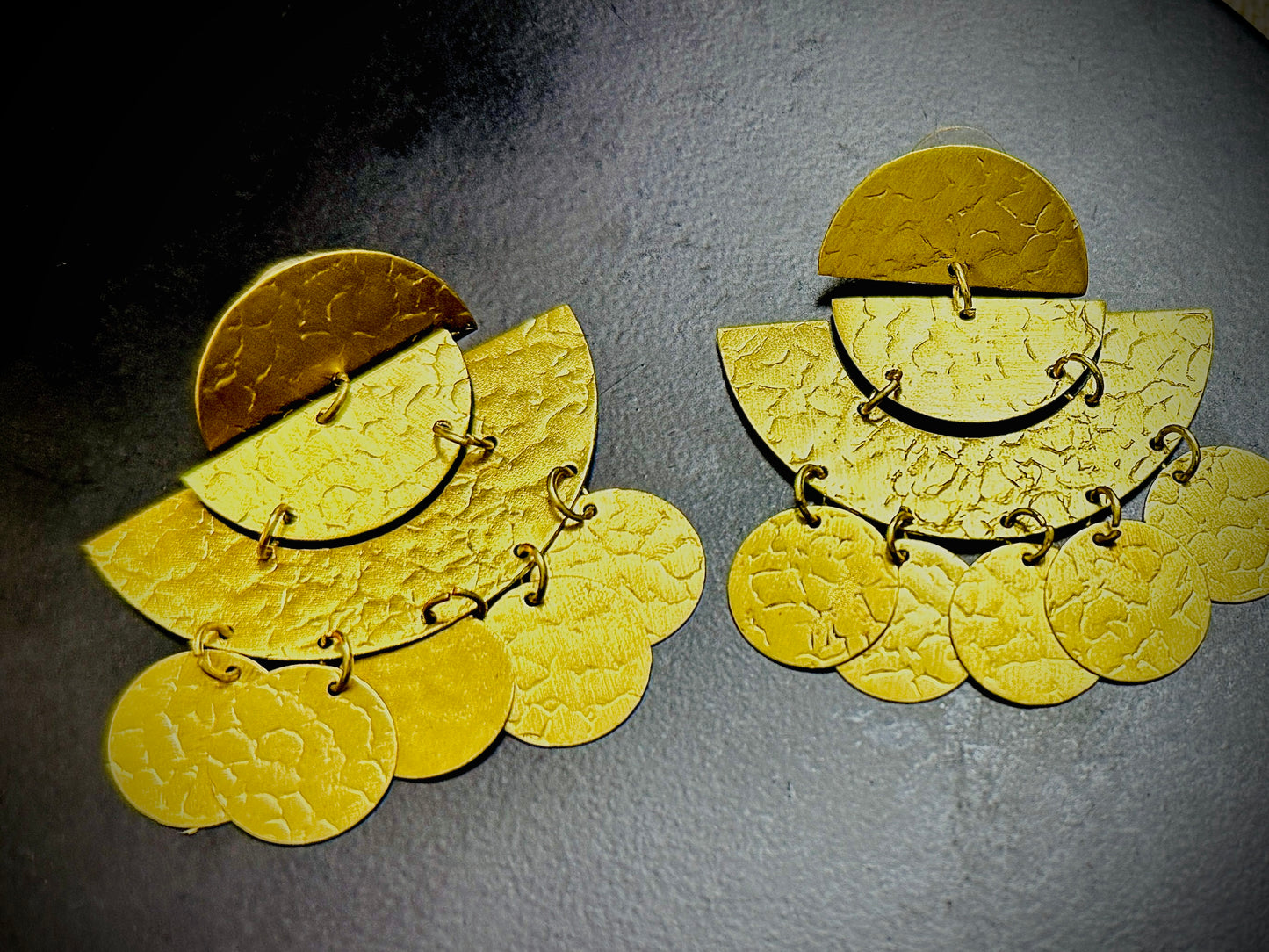 Pair of gold earrings on a dark gray background