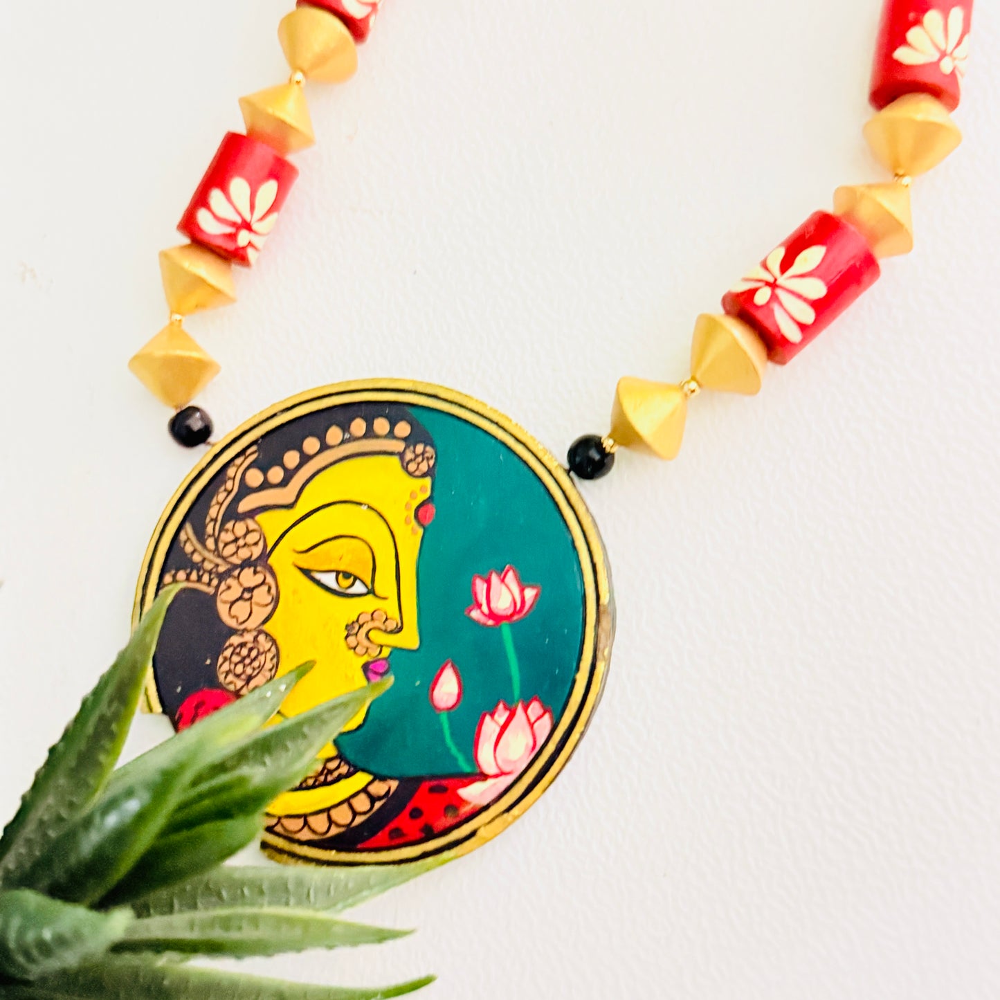Necklace with a decorative pendant featuring a face design on a white background