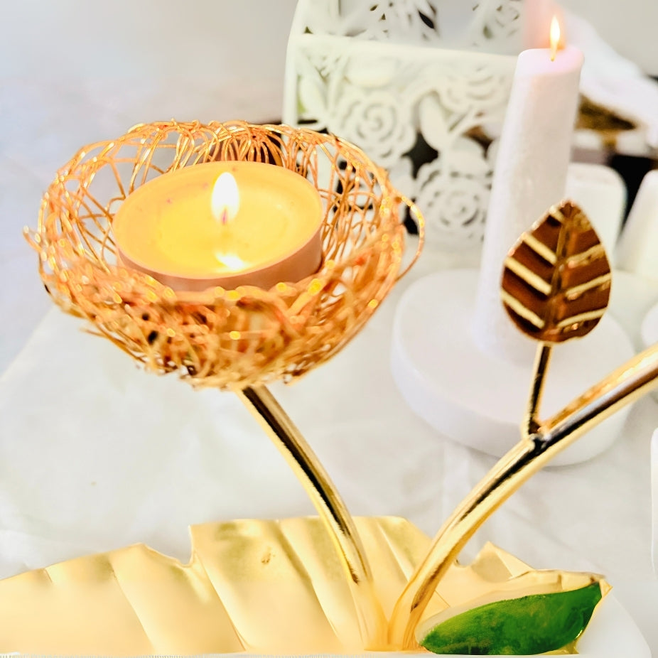 Decorative candle holder with a lit candle, gold leaves, and a white candle in the background.