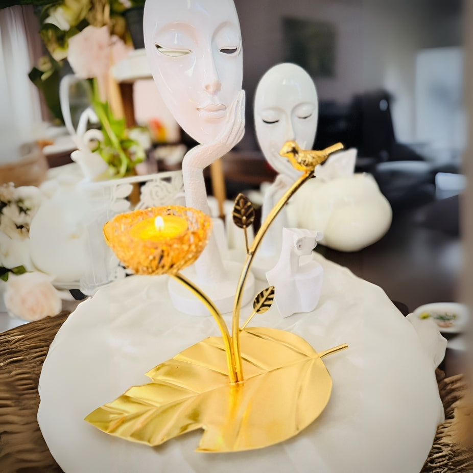 Decorative item with white faces, gold leaves, and a candle on a blurred background