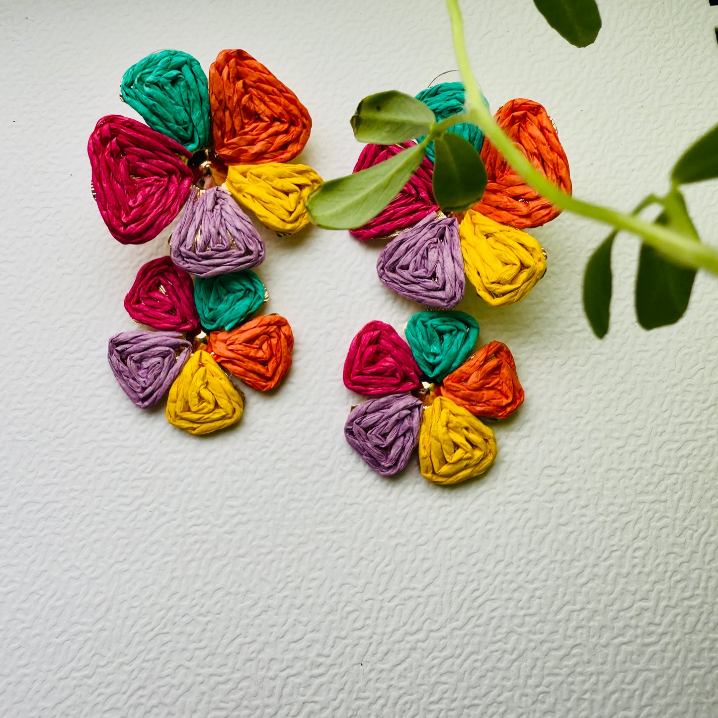 Colorful yarn flower earrings on a textured white background