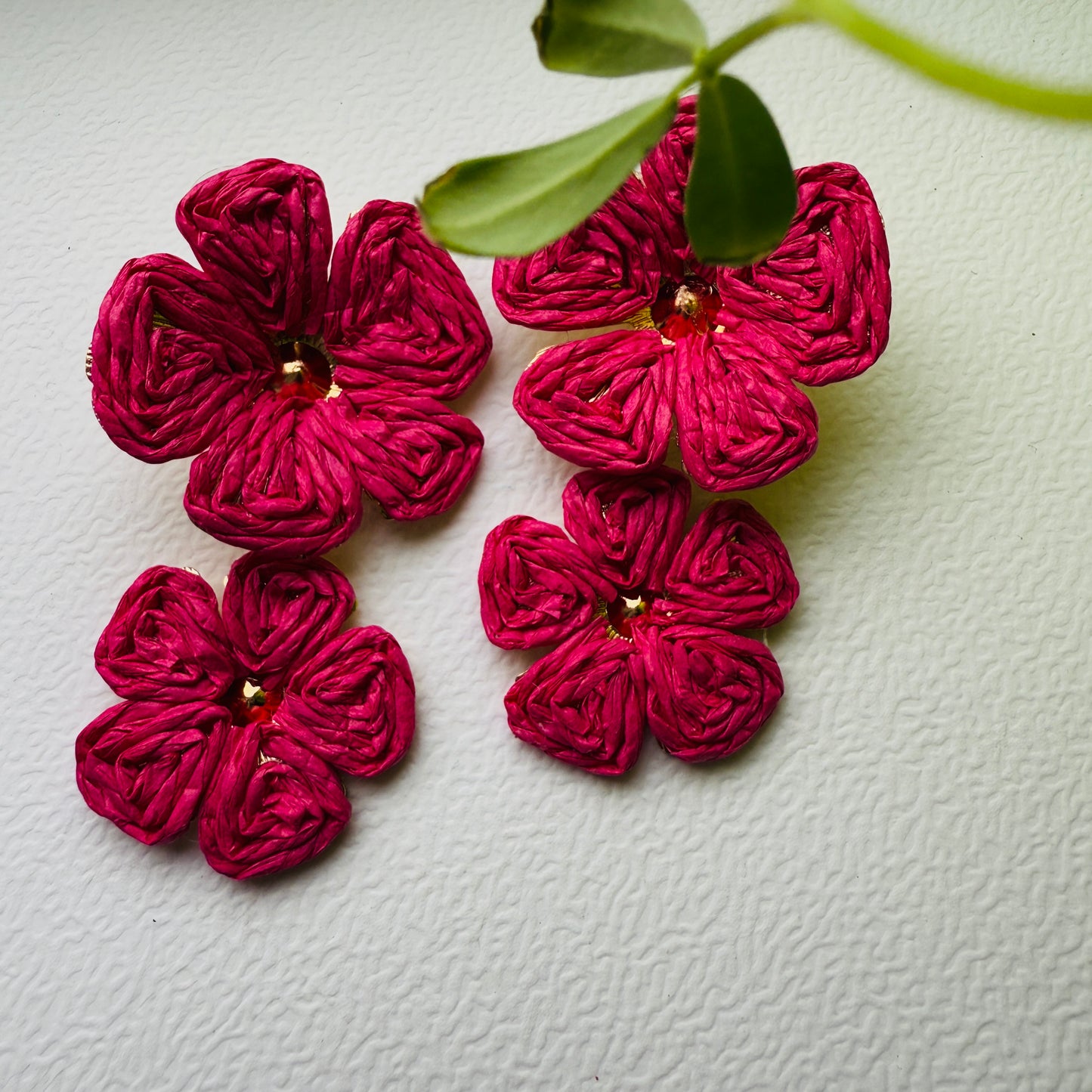 Pink flower-shaped earrings on a textured white background