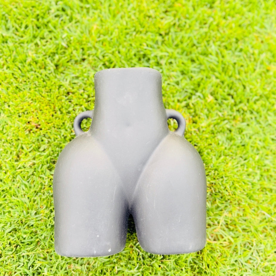 Gray ceramic vase shaped like a pair of pants on green grass