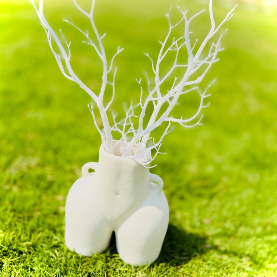 White vase with branches on a green grass background