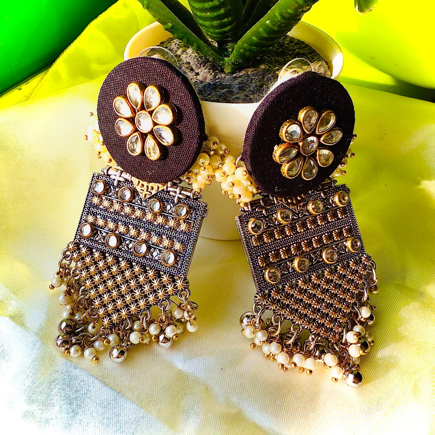 Decorative earrings with floral design on a yellow fabric background
