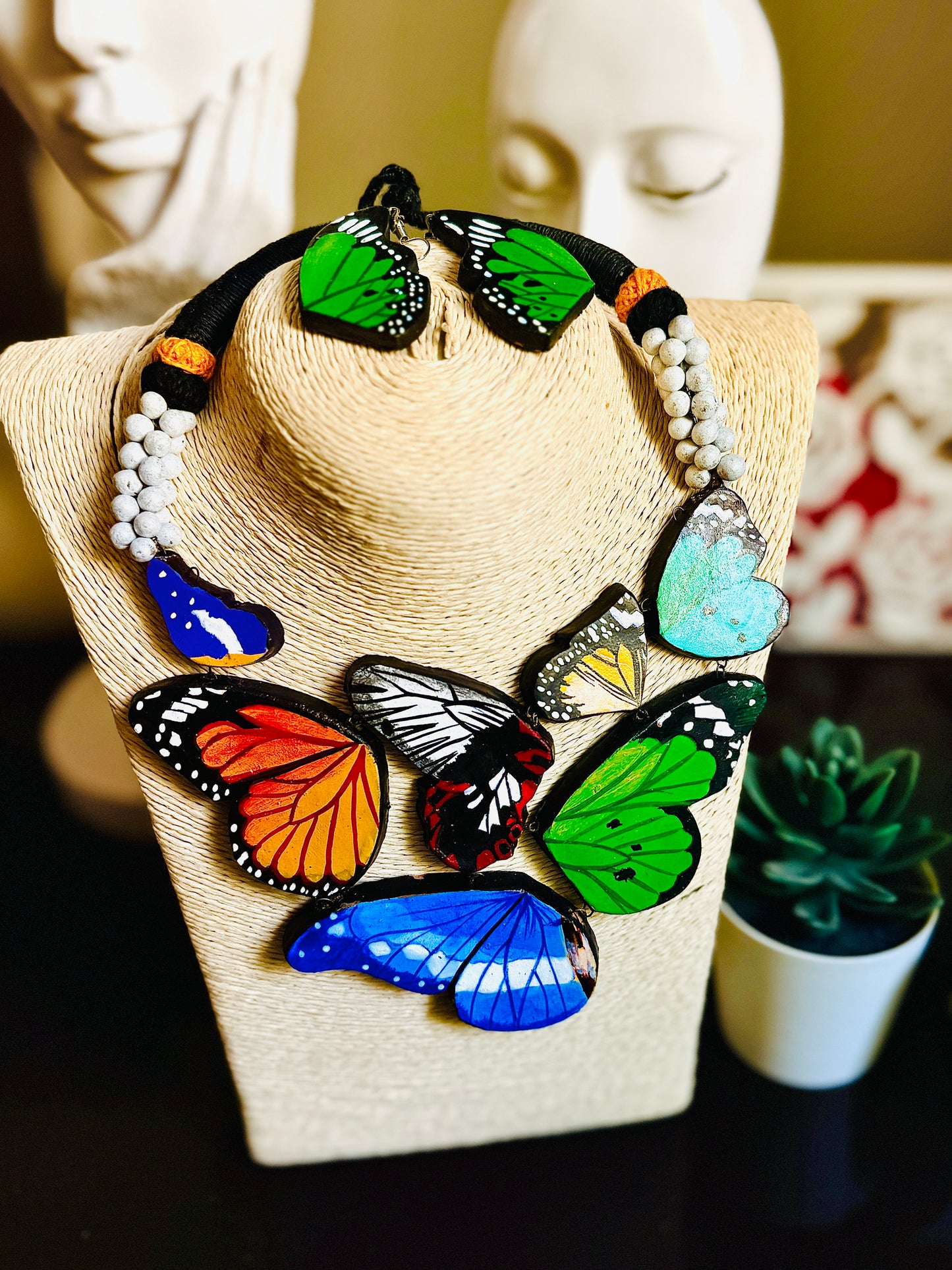 Necklace with colorful butterfly pendants on a mannequin bust.