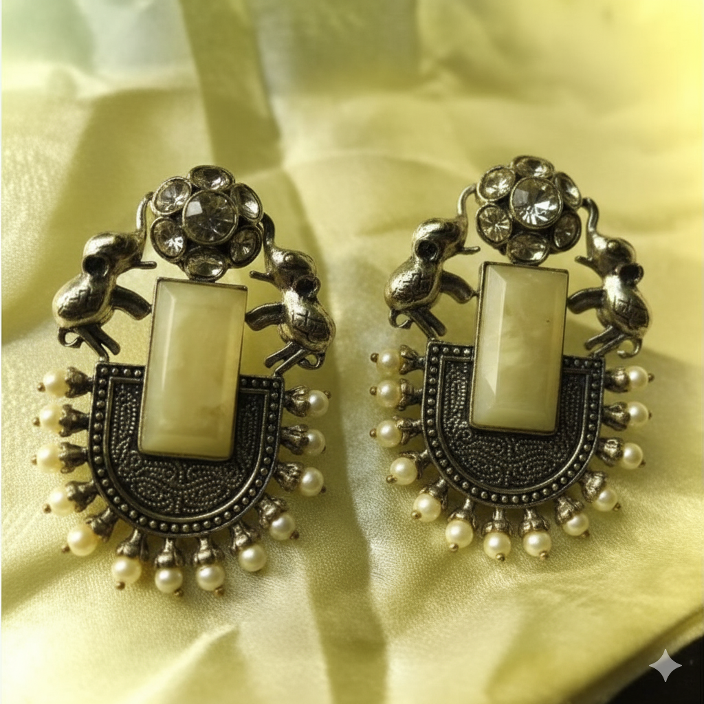 Decorative earrings with intricate designs on a yellow fabric background