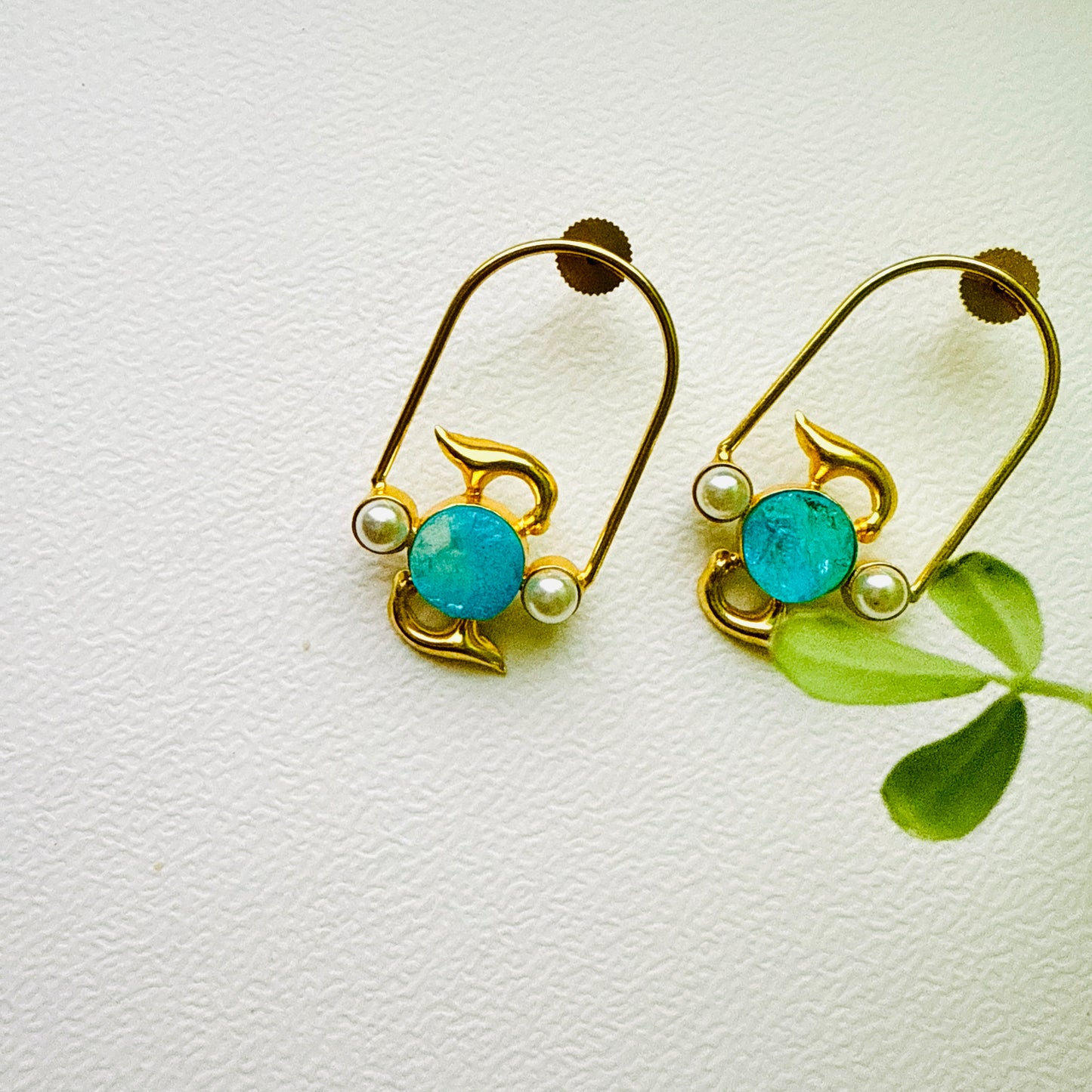 Gold earrings with turquoise stones and pearls on a white background