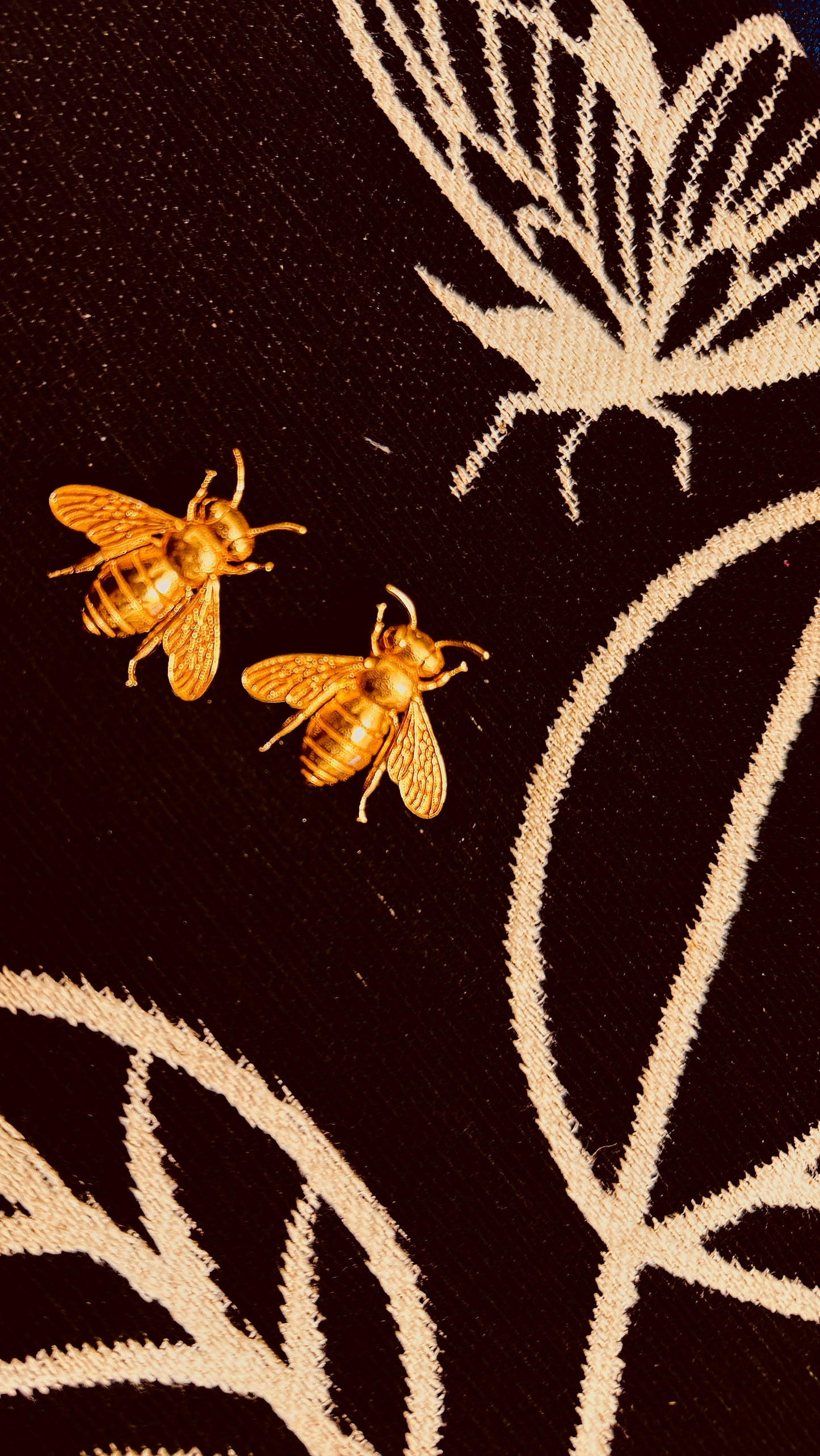 Two bees and a butterfly embroidered on a black fabric background