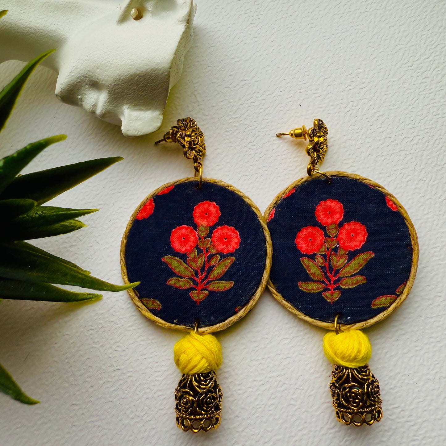 Pair of earrings with floral design and yellow tassels on a white background