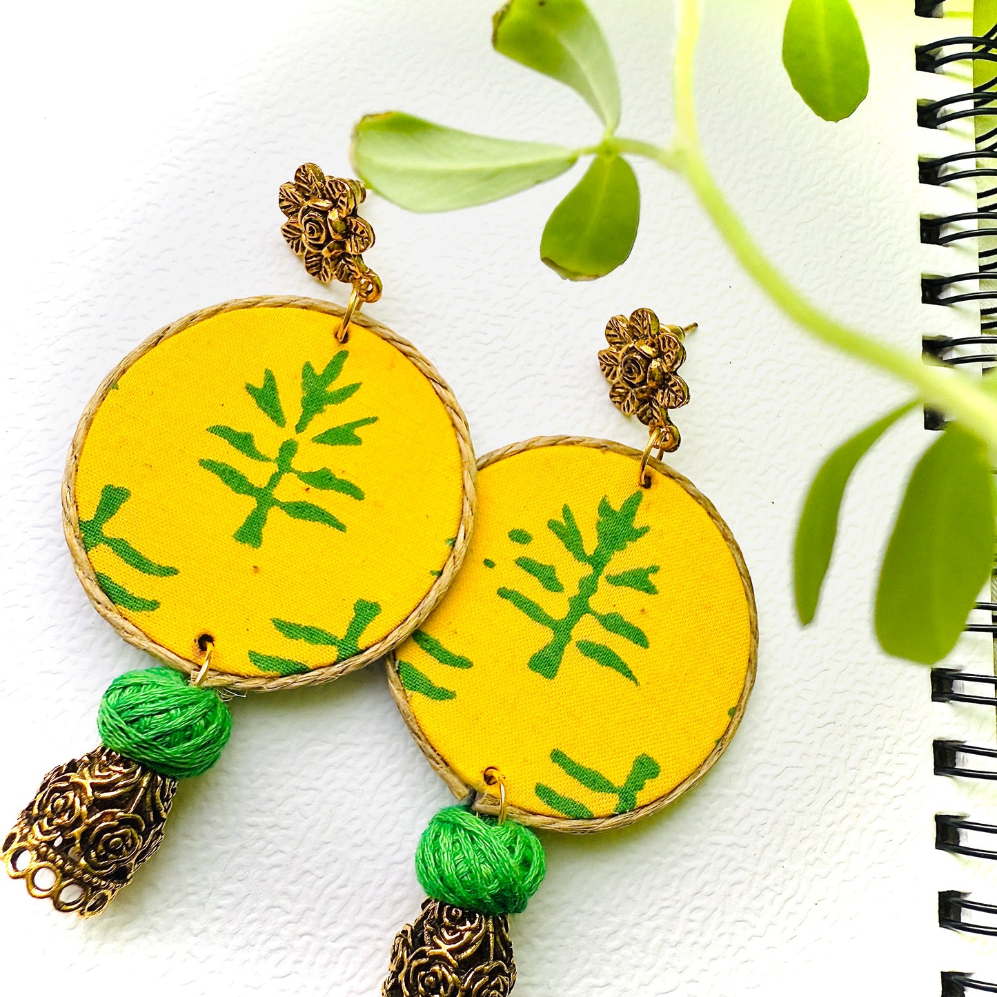 Yellow earrings with green patterns and tassels on a white background