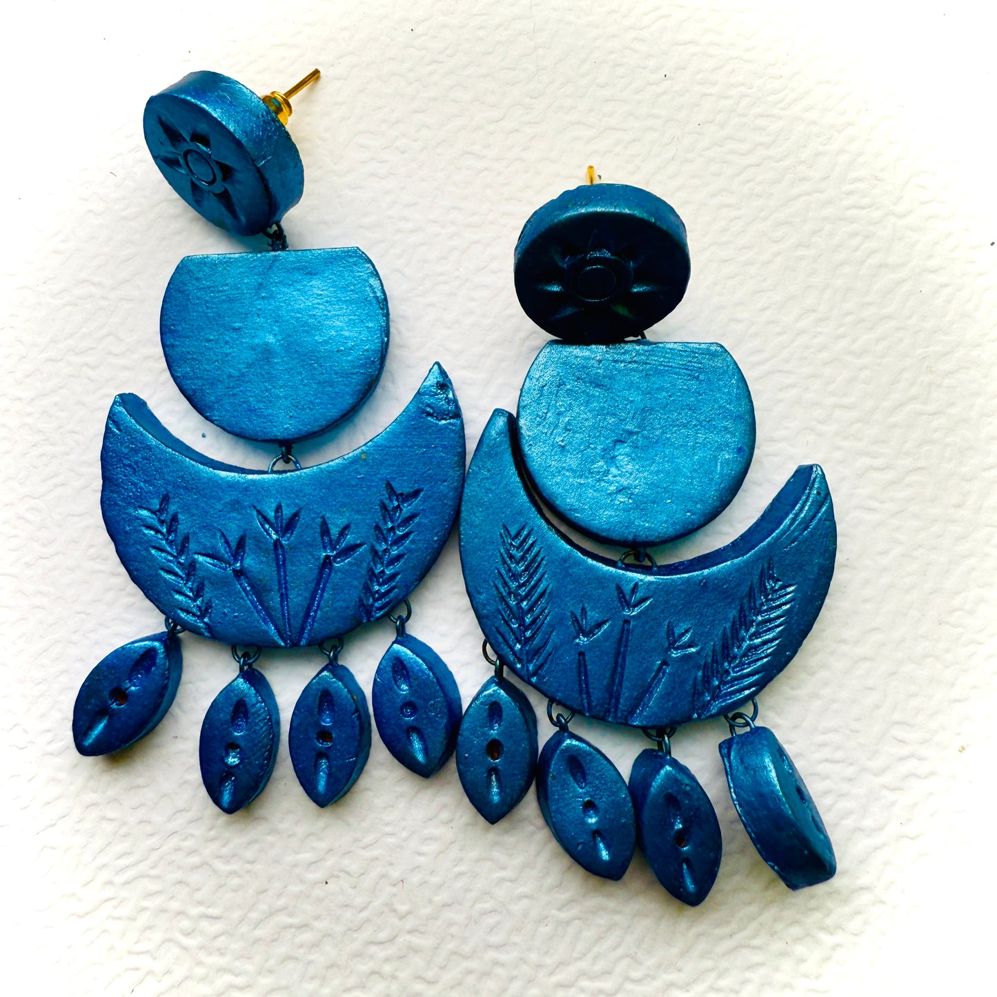 Blue earrings with intricate designs on a white background