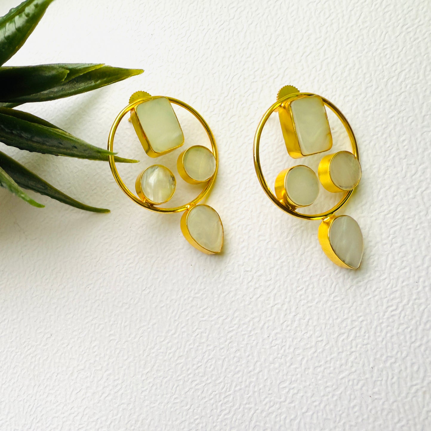 Gold earrings with green stones on a white background