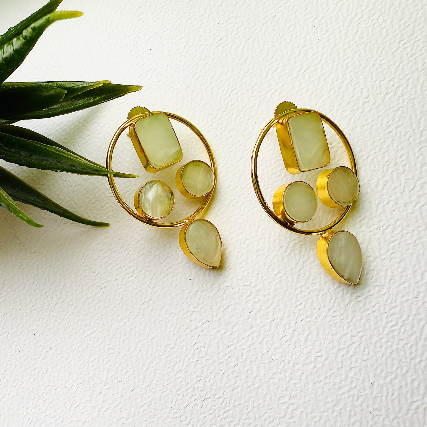 Gold earrings with green stones on a white background