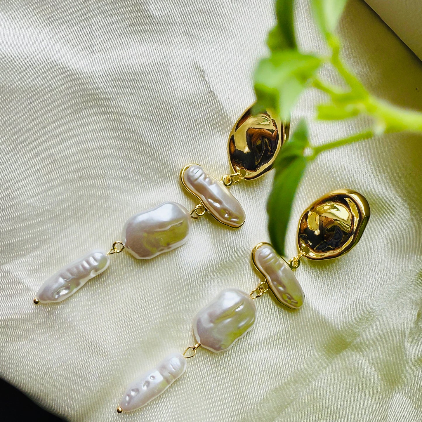Gold and pearl earrings on a light fabric background