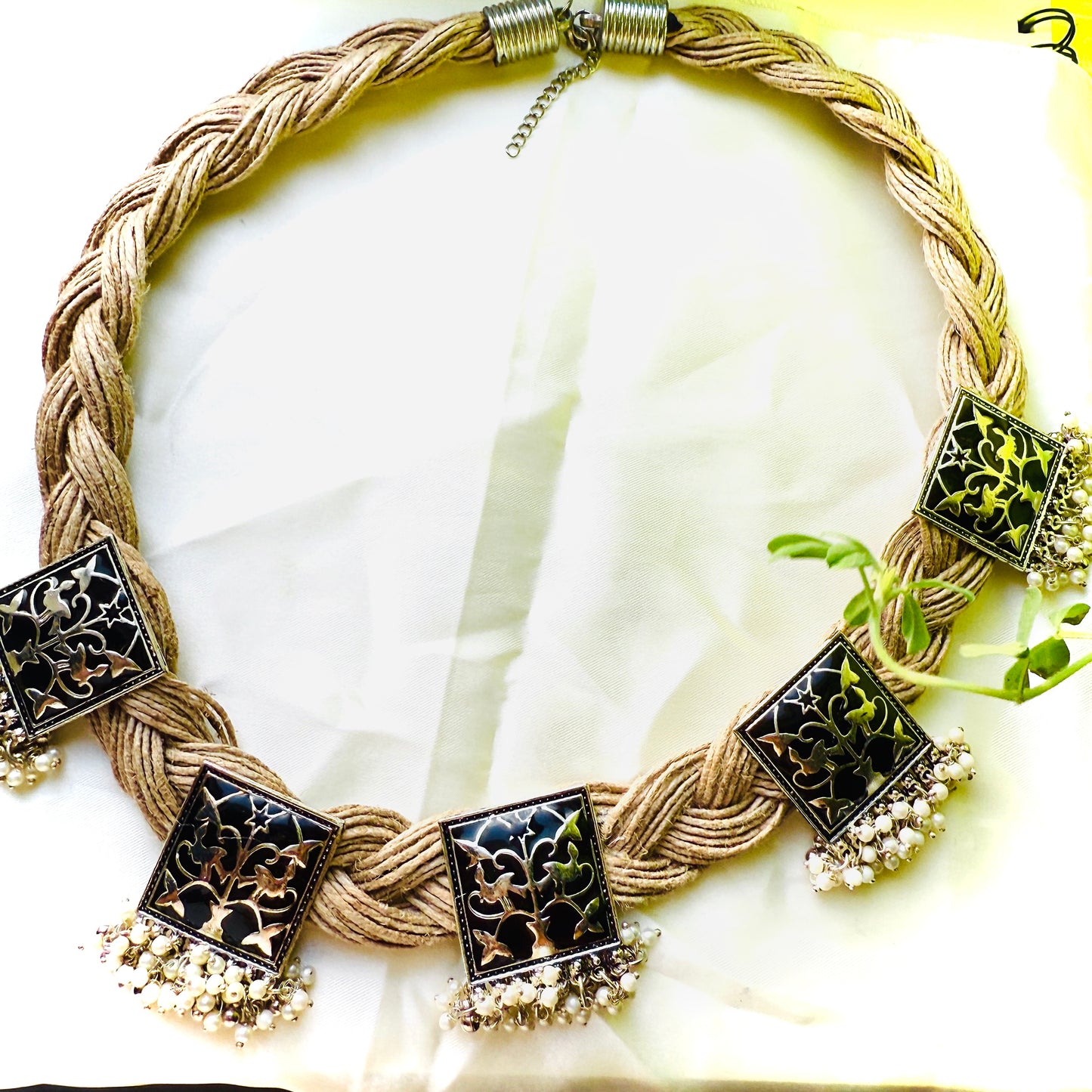 Necklace with braided design and decorative black pendants on a white background