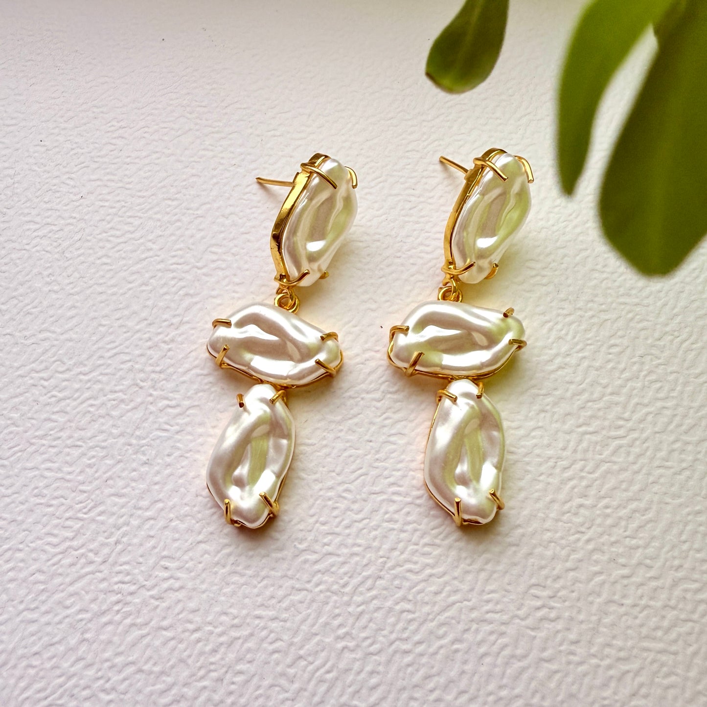 Pair of gold and pearl earrings on a light background