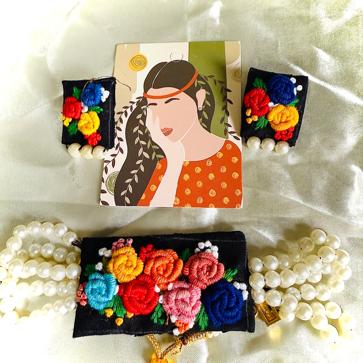 Decorative hair clips with floral designs and pearls on a white fabric background