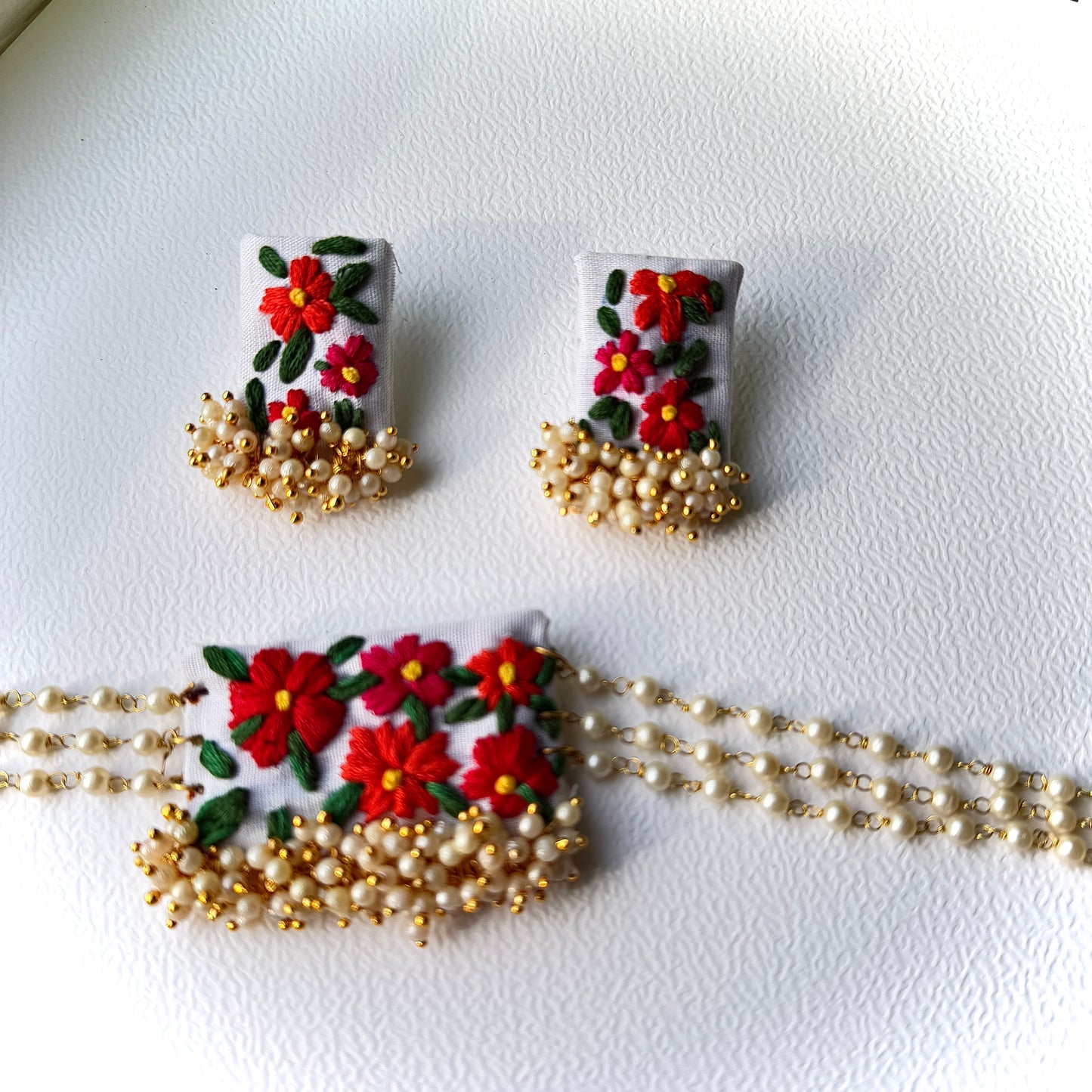 Pair of earrings with floral design and gold chain on a white background
