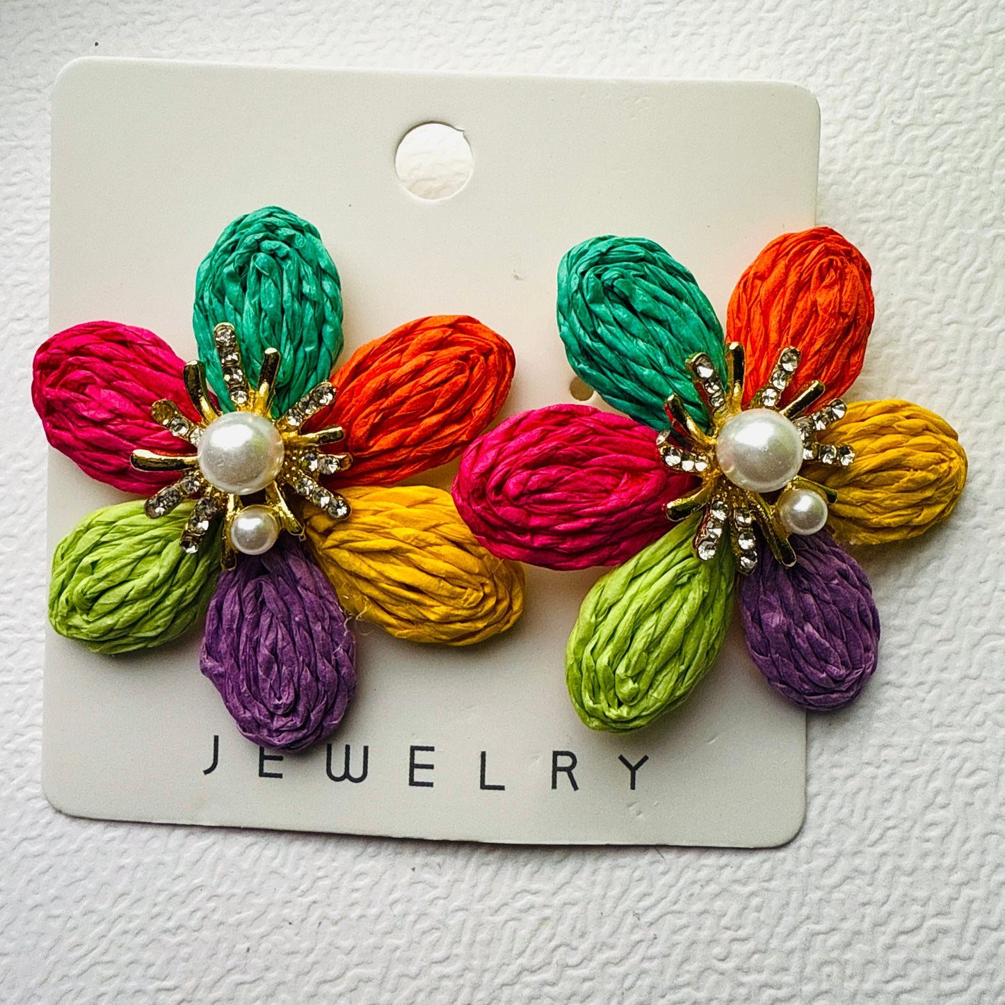 Colorful flower-shaped earrings on a jewelry card against a white background