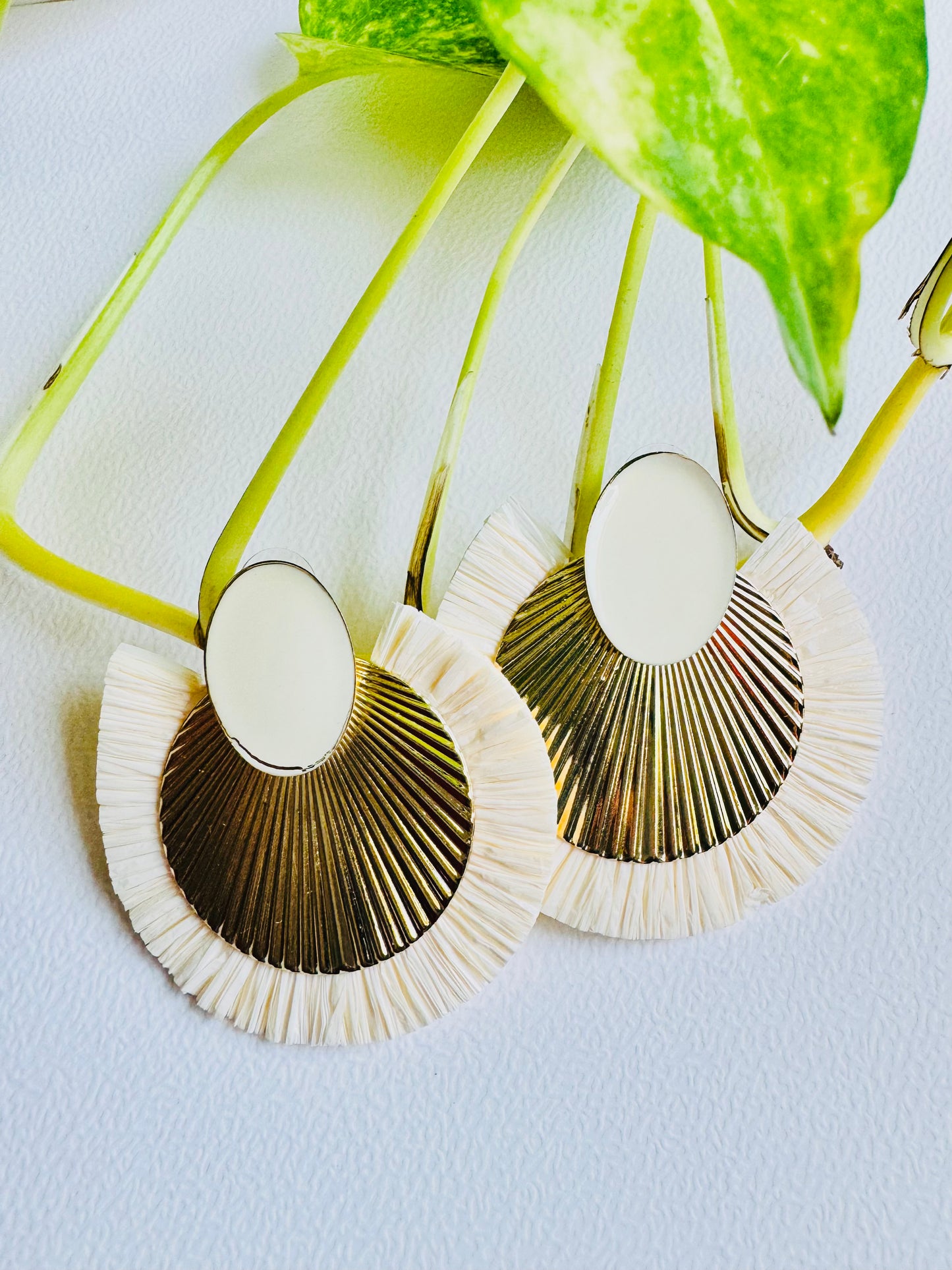 Pair of earrings with gold and white design on a light blue background