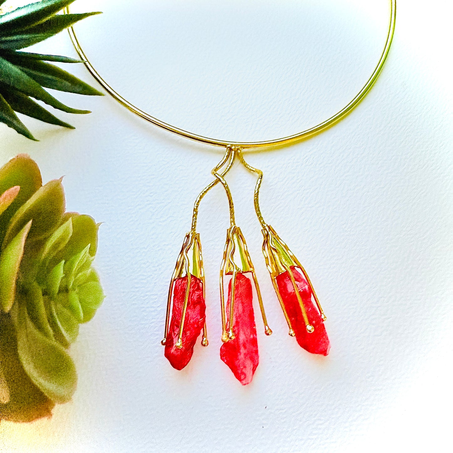 Gold necklace with red pendant on a white background
