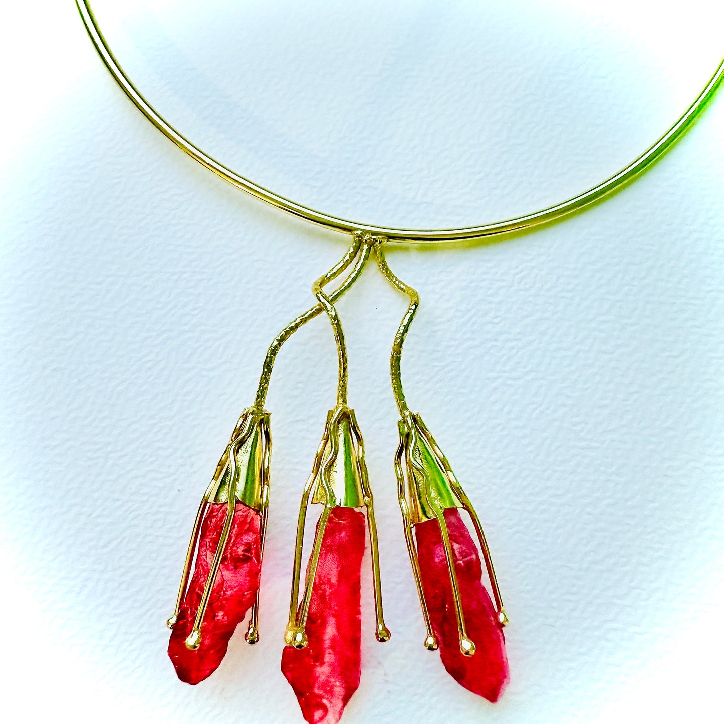 Gold necklace with red pendant on a white background