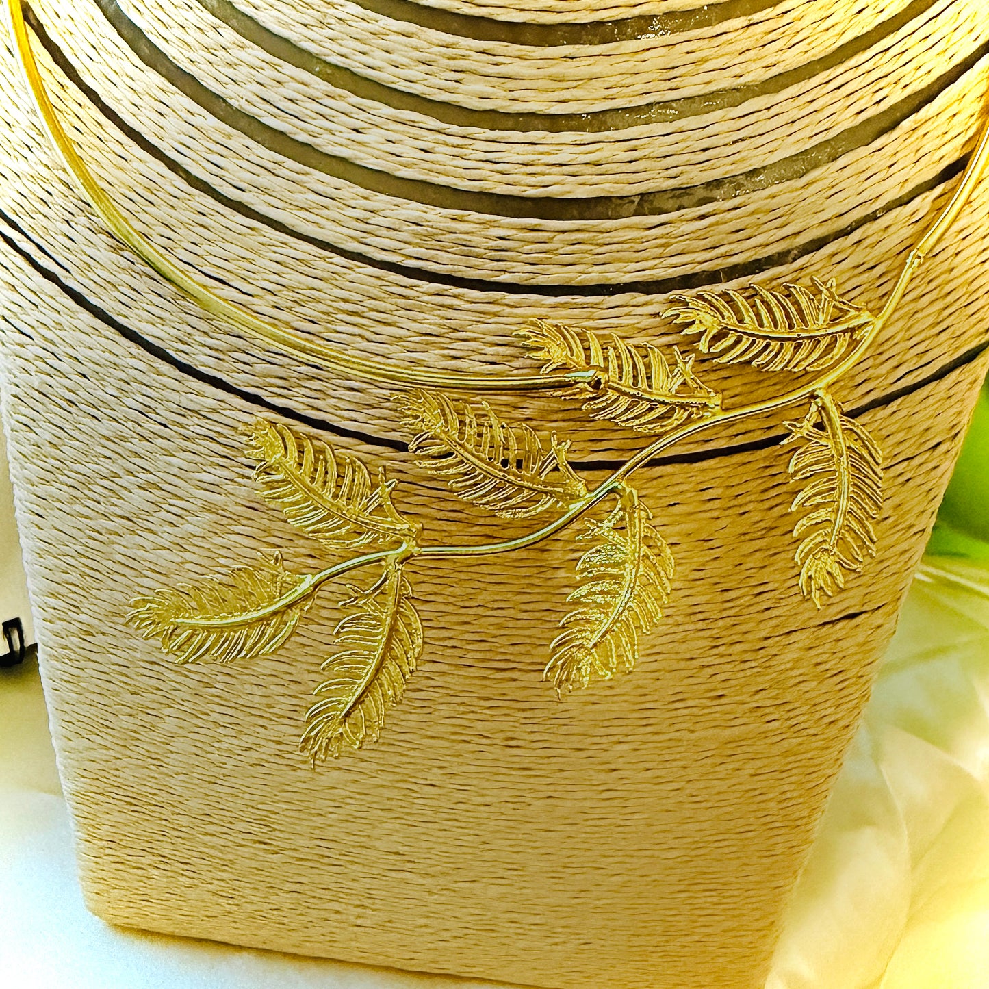 Gold-wrapped cylindrical object with leaf designs on a white background