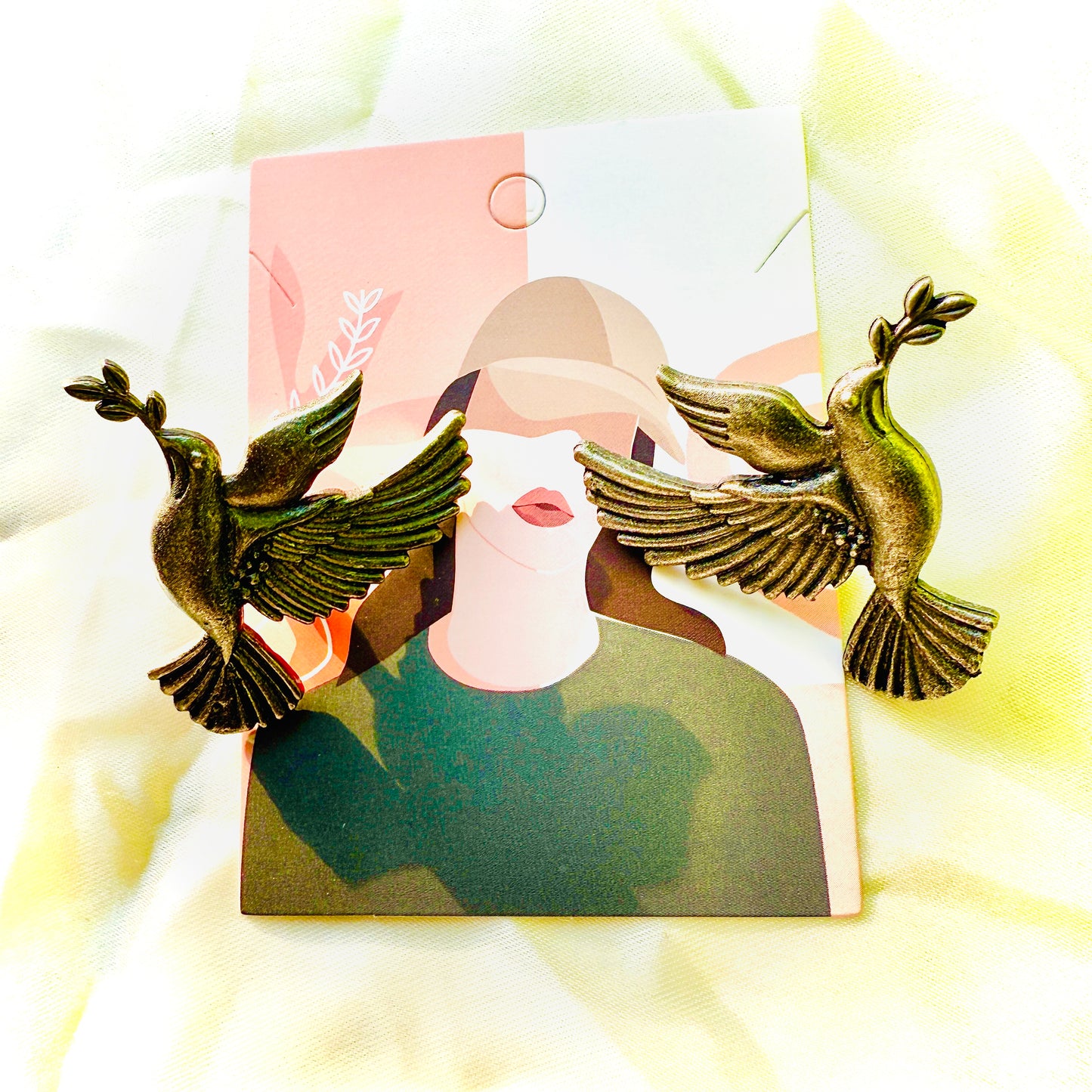 Bronze bird-shaped earrings on a blurred background