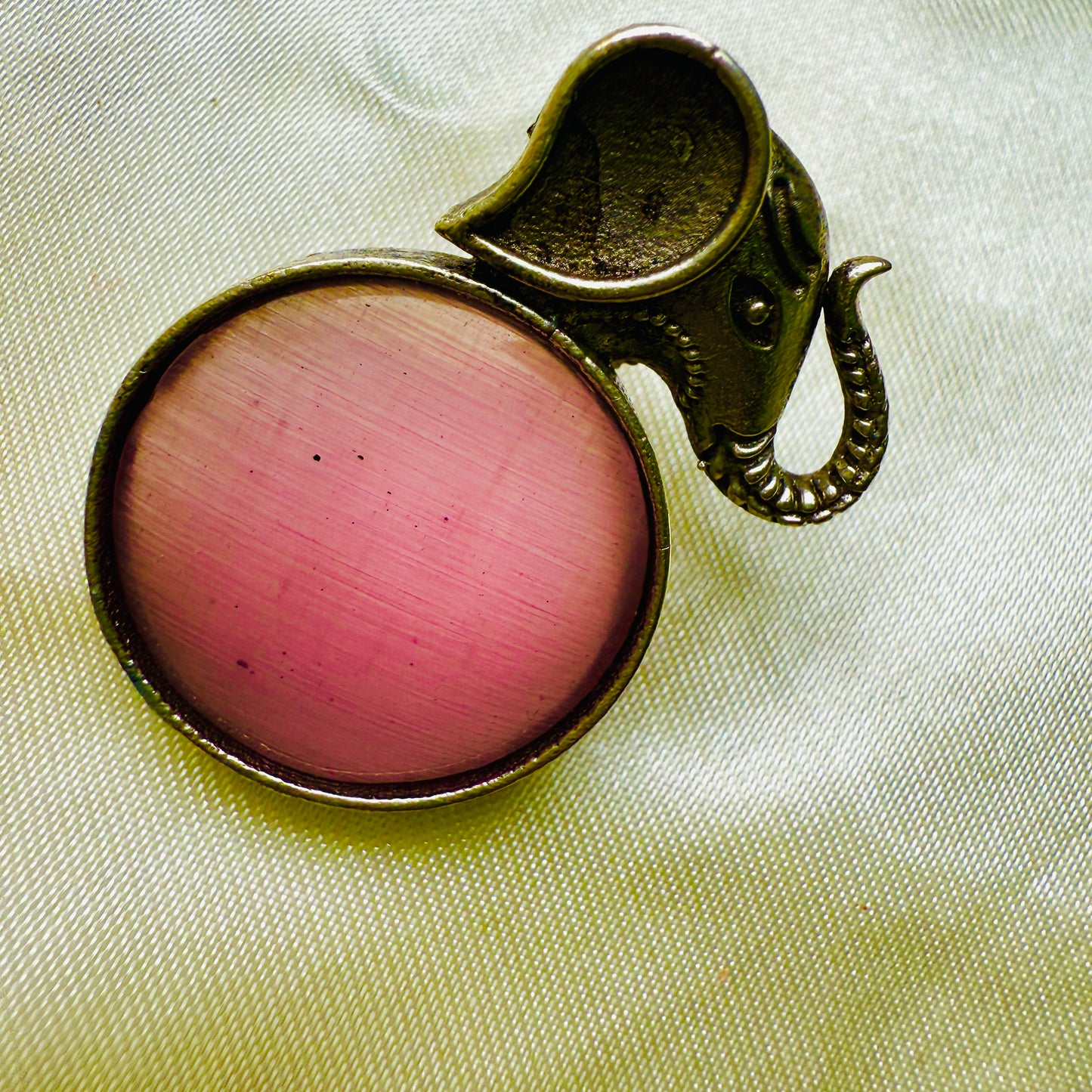 Pink gemstone in a bronze setting on a light fabric background