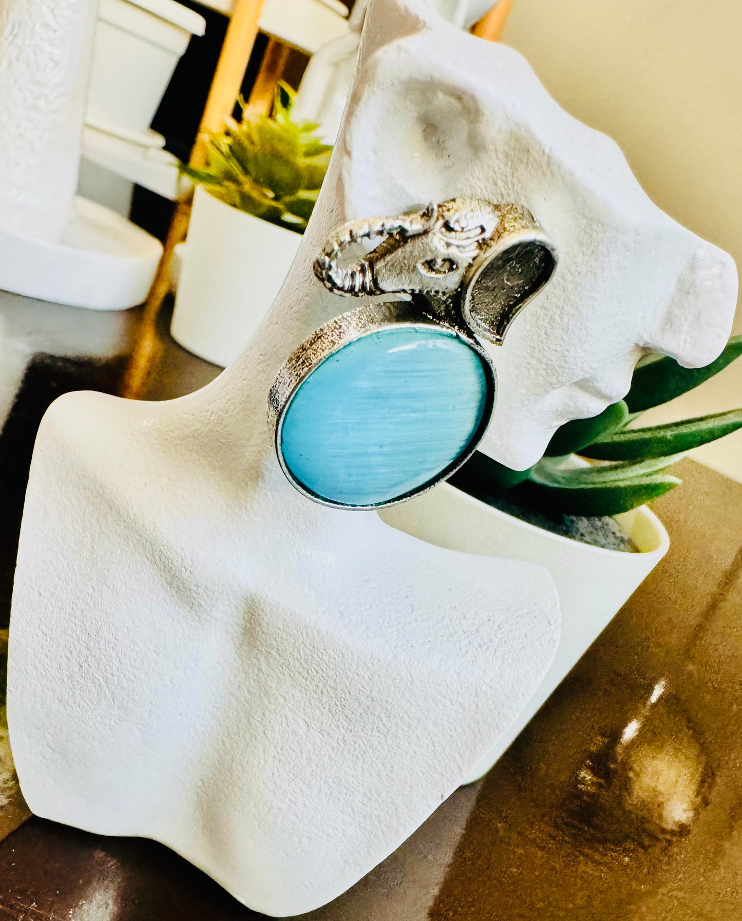 Silver ring with a blue stone on a white stand