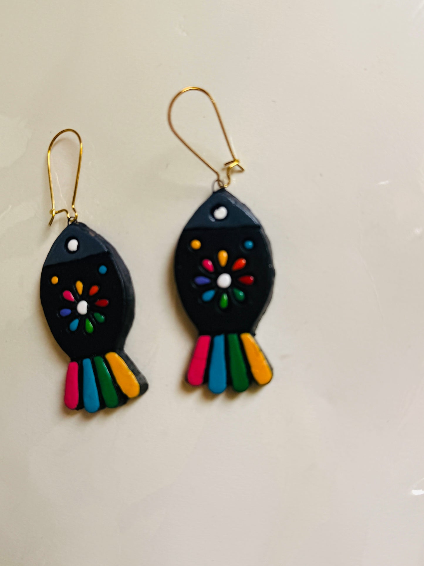 Pair of fish-shaped earrings with colorful designs on a light gray background