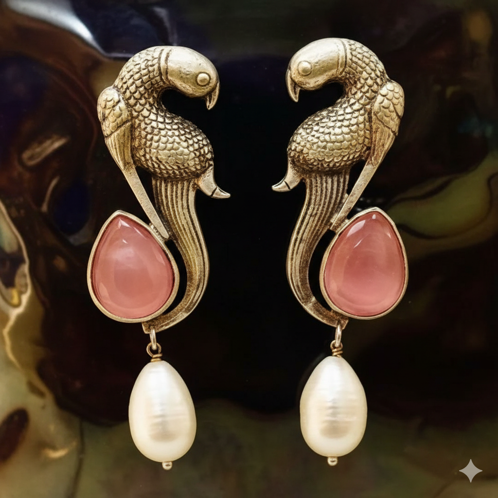 Gold parrot-shaped earrings with pink stones and pearls on a dark background