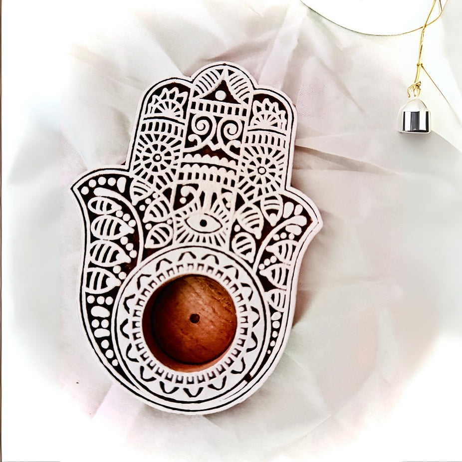 Decorative Hamsa hand with a wooden ball on a light fabric background