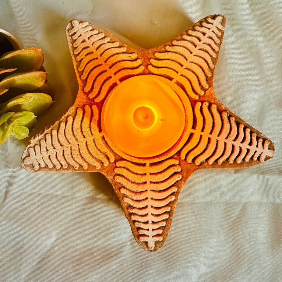 Star-shaped candle holder with a lit candle on a light fabric background