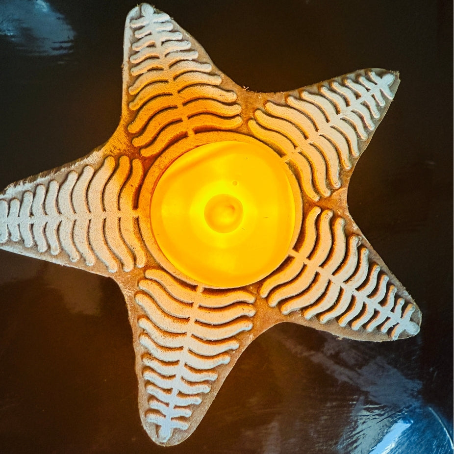 Star-shaped candle holder with wavy patterns on a dark surface