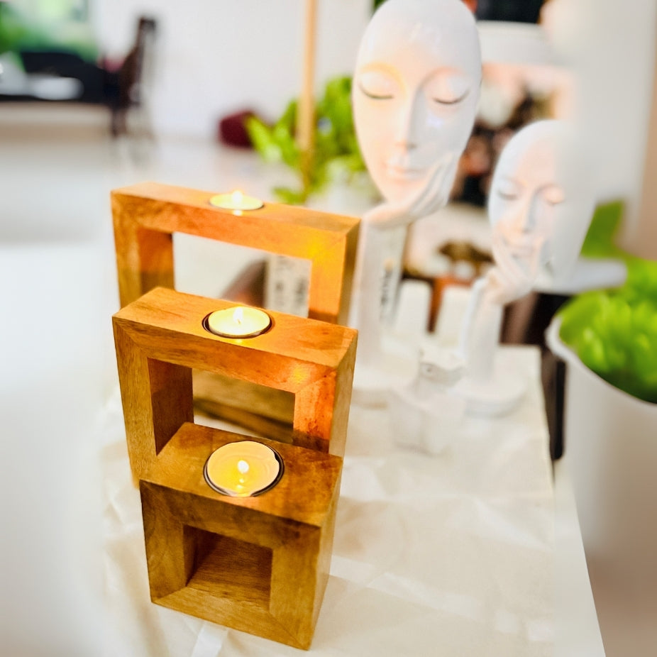 Wooden candle holder with three tea light candles on a blurred background