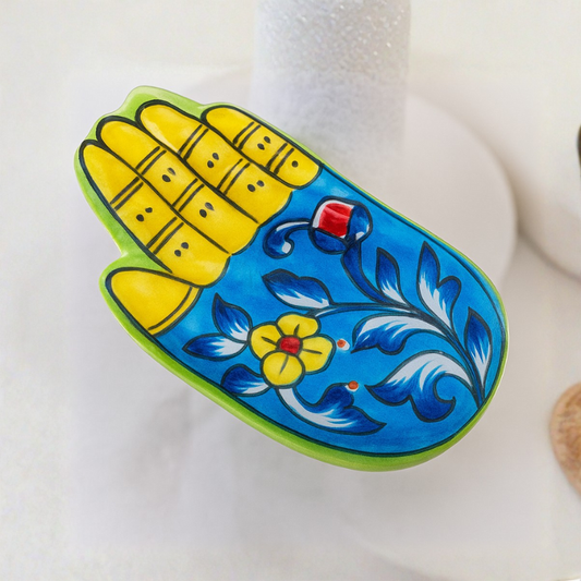 Decorative item shaped like a hand with blue and yellow design on a white background