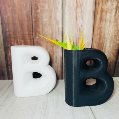 Black letter 'B' mug with green plant against a wooden background