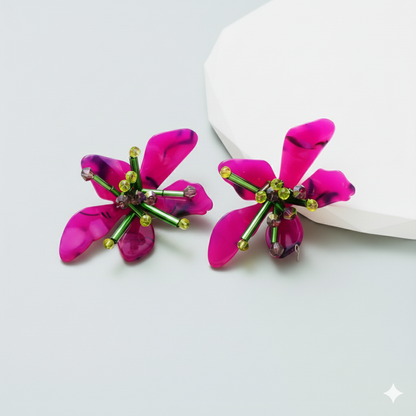 Pink flower-shaped earrings with green accents on a light gray background