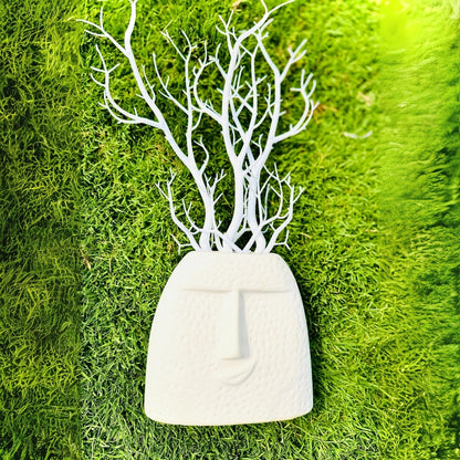 White decorative wall art with tree branches on a green moss background