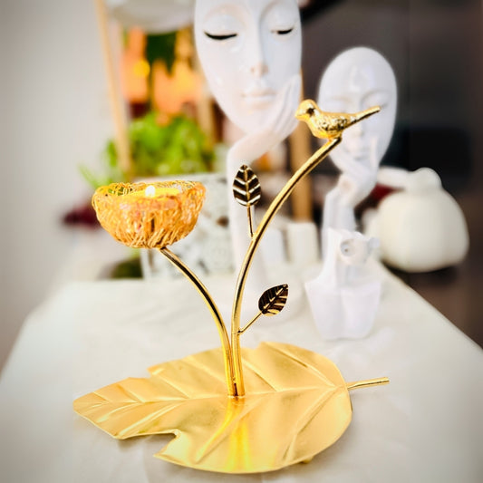 Decorative gold candle holder with leaf design on a white surface.