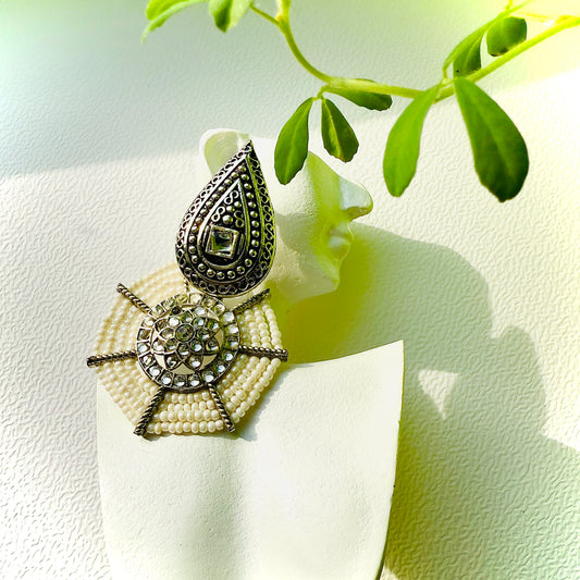 Decorative earring on a white background with green leaves