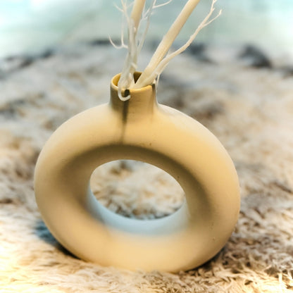 Yellow ceramic vase with a circular design on a textured surface