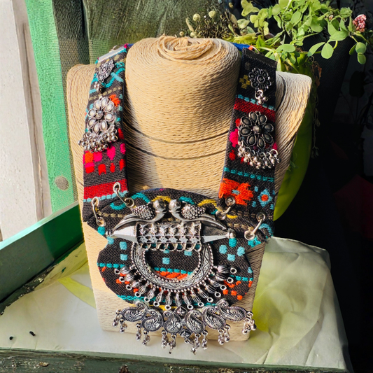 Colorful embroidered belt with intricate silver designs on a mannequin stand.
